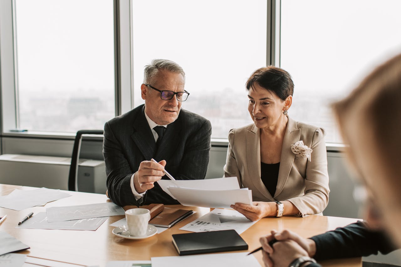 Home Senior business professionals discussing documents in a corporate office setting.